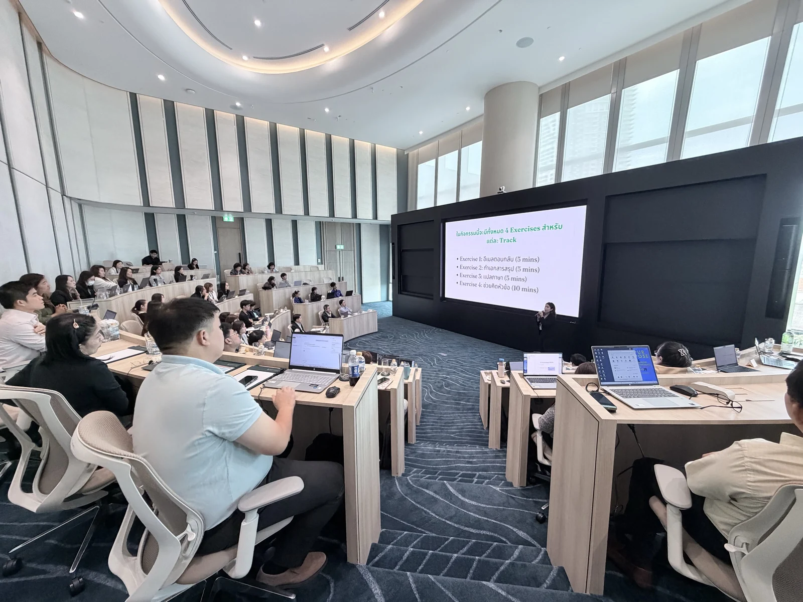 Participants using laptops during a guided session in a tiered classroom.