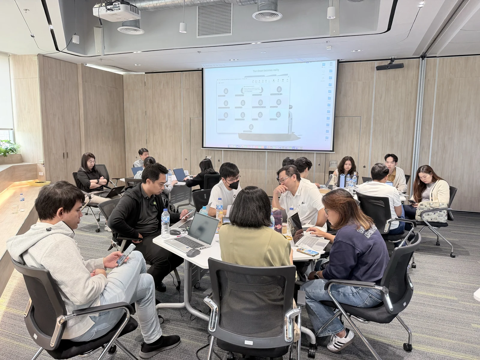 Workshop participants discussing a task around tables with laptops.