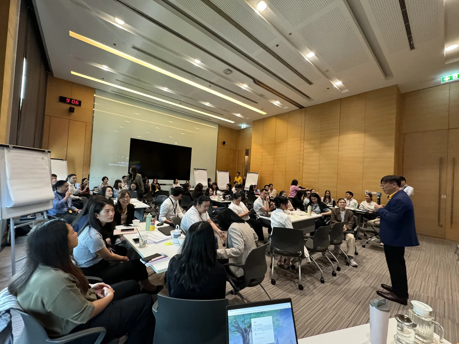 A facilitator and participants working around tables with laptops.